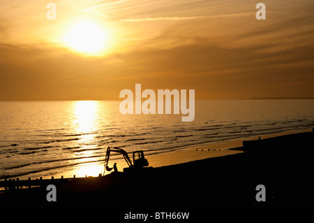 Sonnenuntergang über Brighton Beach, während Arbeiter zum Meer Abwehrkräfte, Brighton, East Sussex, England besuchen Stockfoto