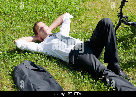 Geschäftsmann Gras neben dem Fahrrad genießen Sie die Sonne liegend Stockfoto