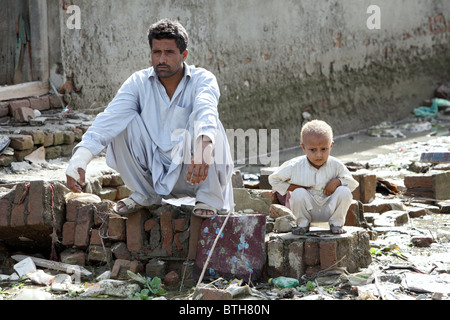 Vater und Sohn sitzen hoffnungslos in einer zerstörten Straße, Nowshera, Pakistan Stockfoto