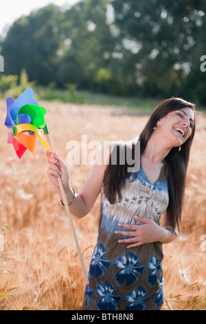 Junge Frau mit Windrad im Weizenfeld Stockfoto