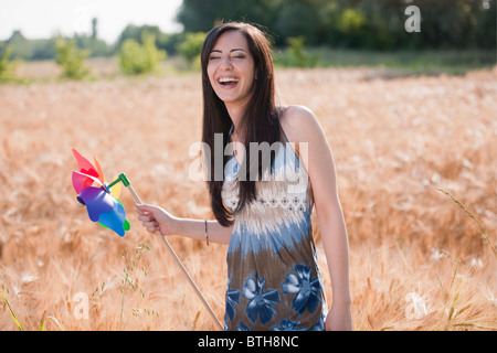 Junge Frau mit Windrad im Weizenfeld Stockfoto