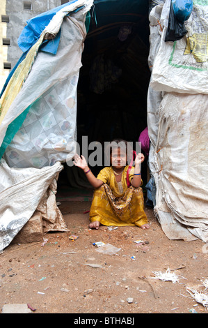 Arme indische Mädchen am Eingang von ihr Zelt nach Hause sitzen aus Kunststoff Säcke über einen Holzrahmen. Andhra Pradesh, Indien Stockfoto