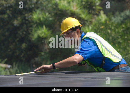 Instandhalter misst Solaranlage auf Dach, Los Angeles, Kalifornien Stockfoto