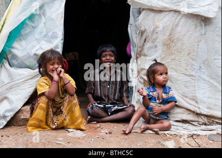 Armen indischen Mädchen und Jungen am Eingang von Ihrem Zelt zu Hause sitzen. Andhra Pradesh, Indien Stockfoto