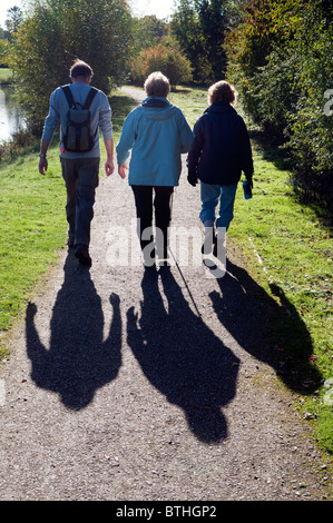 Silhouette von der Rückseite der drei Wanderer und ihre Schatten zu Fuß auf einem Fußweg am Ufer des Flusses Jubiläum. Stockfoto