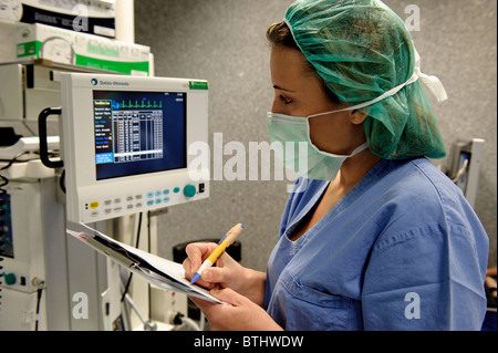 Krankenschwester prüft einen Monitor mit der Patientin Eingeweide während einer Operation in einem Krankenhaus-OP-Saal Stockfoto