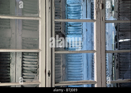 Zerbrochenes Glas und Holz Peeling Fensterhintergrund Fensterläden verfallenes Haus. Stockfoto