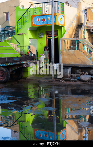 Bunte indische Straße Szene nach dem Regen mit Mädchen und Kuh an die Tür eines Hauses in der Stadt Puttaparthi, Andhra Pradesh, Indien Stockfoto