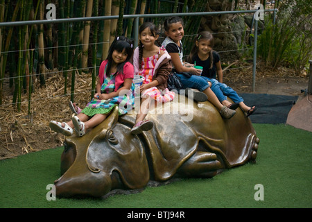 Vier junge Mädchen sitzen auf einem geformten Metall Nilpferd im ZOO von SAN DIEGO - CALIFORNIA Stockfoto