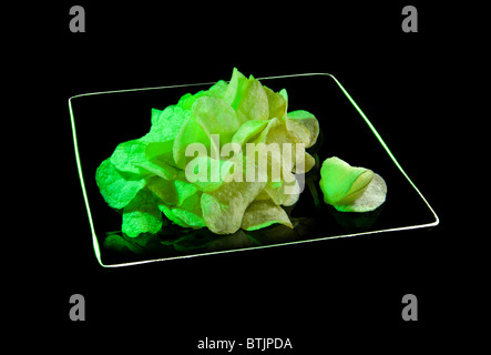 grüne Wasabi-chips Chips Kartoffeln auf schwarze Platte Essen junk Fett pikante Würze grüne Wasabi geröstet mit Wasabi Rumpf Auslauf Wrapper co Stockfoto