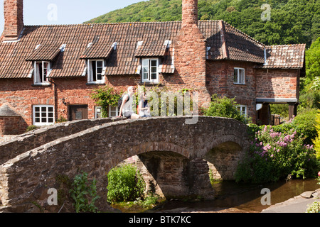 Ein paar Touristen genießen die Aussicht vom alten Pack Pferd Brücke über den Fluss Aller Allerford, Exmoor, Somerset Stockfoto