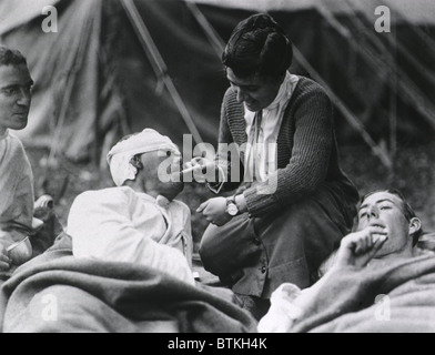 Rotes Kreuz Arbeiter Miss Anna Rochester, des Smith College Referats, hilft einen verwundeten Soldat mit seiner Zigarette in der US-Armee Evakuierung Klinik Souilly, Frankreich während Erster Weltkrieg I. Ca. 1917-18. Stockfoto