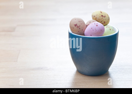 Ein Eierbecher, gefüllt mit bunten Osterei Süßigkeiten, auf einem Holztisch Birke. Kopieren Sie Raum auf der linken Seite. Stockfoto