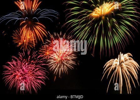 Mehrere Ausbrüche von glänzend bunten Feuerwerk gegen einen schwarzen Himmel Stockfoto