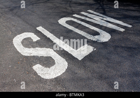 Langsamere Zeichen gemalt auf schwarzem Asphalt auf einer Landstraße im Vereinigten Königreich Stockfoto