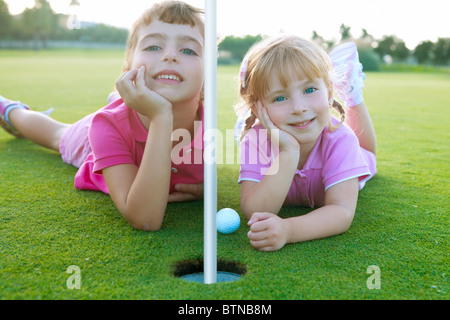 Golf zwei Schwester Mädchen entspannt liegen in der Nähe von grünen Loch mit Ball Stockfoto