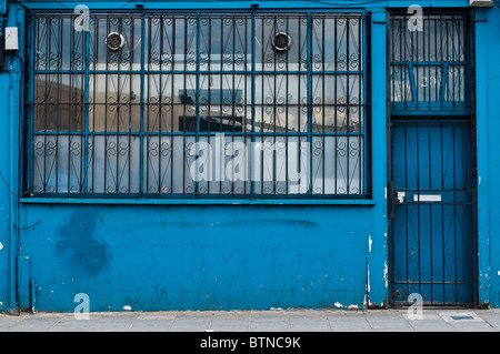 Ein blaues Gebäude in Dalson Balken an der Tür und den Fenstern im Erdgeschoss aus Sicherheitsgründen. Stockfoto