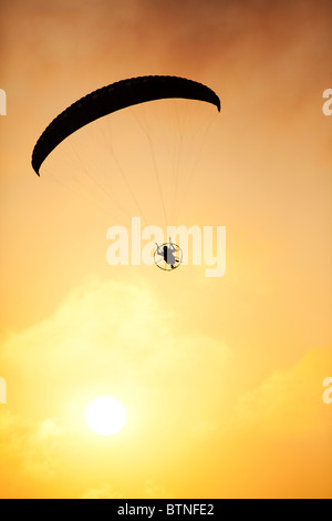 Silhouette von einem angetriebenen Para Segelflugzeug fliegen in Richtung eines brillanten Sonnenuntergangs. Stockfoto