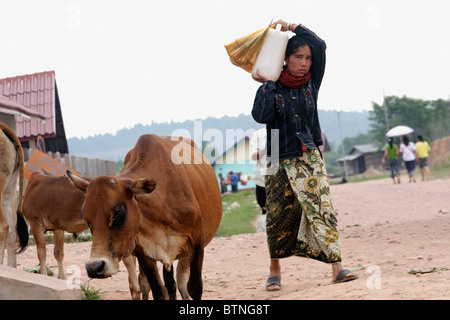 Eine Frau trägt eine große Flasche Trinkwasser auf die Schulter in der Nähe von den wichtigsten Markt in Muang Sing, Laos. Stockfoto