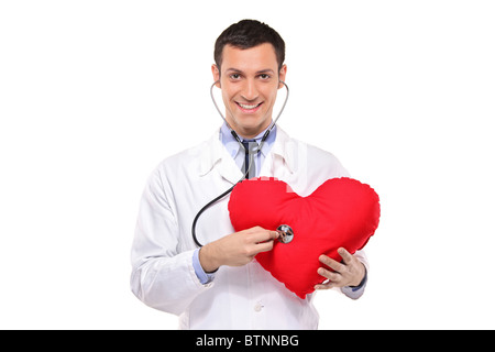 Ein Lächeln auf den Lippen Arzt untersuchen eine rotes Herz geformten Kissen mit einem Stethoskop Stockfoto