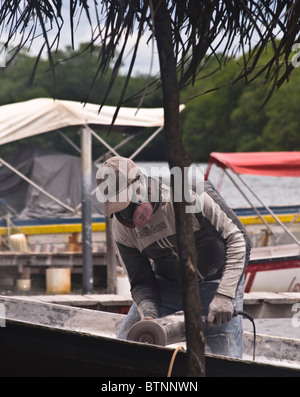 Fischer mit einer Schleifmaschine, Durchführung von Reparaturen an seinem Boot in Baru, Kolumbien Stockfoto