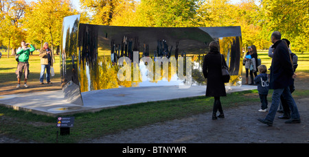 Besucher, die in den Kensington Gardens sind, sehen reflektierte Bilder von sich selbst in einem der Anish Kapoor Sky Mirrors C Curve London England UK Stockfoto