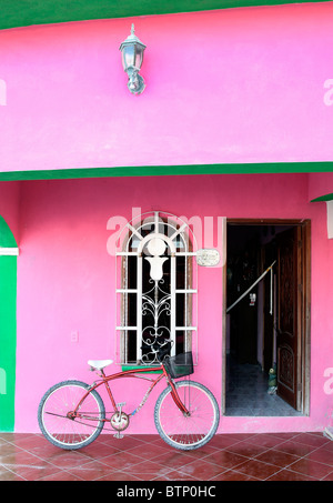 Roten Fahrrad stützte sich auf ein sehr bunt, rosa und Grün Haus auf Isla Holbox, Bundesstaat Quintana Roo, Mexiko Stockfoto