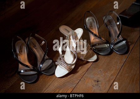 Bräute & Brautjungfern Sandalen zusammen in einem Pool von Licht in einem dunklen Holzboden warten auf die Braut feiern Stockfoto