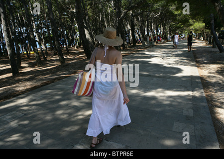 Eine junge Dame Spaziergänge entlang der schattigen Allee in der Nähe von Strand von Bol auf der Insel Brac, Kroatien Stockfoto