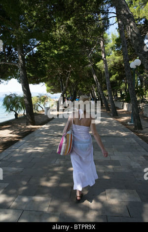 Eine junge Dame Spaziergänge entlang der schattigen Allee in der Nähe von Strand von Bol auf der Insel Brac, Kroatien Stockfoto