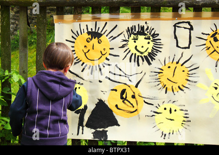 Babymädchen malt die Sonne auf der großen Papier im freien Stockfoto