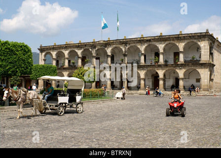 Pferd und Wagen und ATV vor der Palacio de Ayuntamiento oder Rathaus mit Blick auf den Parque Central, Antigua, Guatemala. Stockfoto