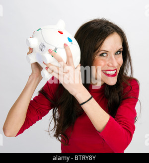 Hübsche Frau untersucht Sparschwein Stockfoto