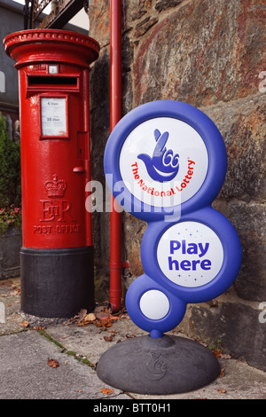 Die Nationale Lotterie spielen hier' Zeichen außerhalb einer Post mit britischen Briefkasten. Großbritannien, Großbritannien. Stockfoto