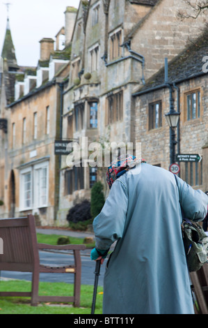 Alte Dame geht auf der Straße in der Cotswold-Dorf Broadway. Worcestershire, England. Stockfoto