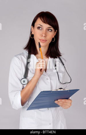 Junge Ärztin zuversichtlich in nachdenklicher Pose für ärztliche Untersuchung bereit. Stockfoto