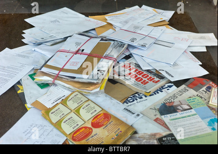 ein Haufen von ungeöffnete Post auf der Fußmatte eines stillgelegten Unternehmens Stockfoto