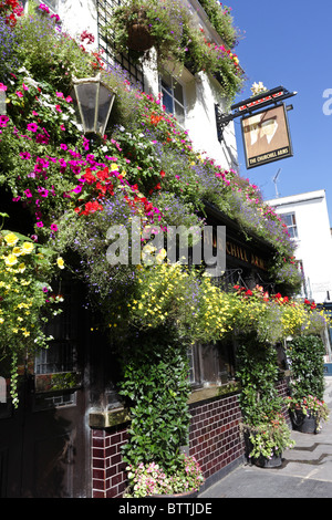 Wunderbar arrangierte Blume zeigt schmücken die Außenfassade des beliebten Churchill Arms Pub in Kensington. Stockfoto