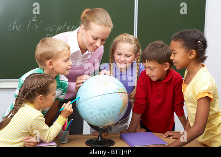 Porträt von Schülern Blick auf Globus beim hören Lehrer im Erdkundeunterricht Stockfoto