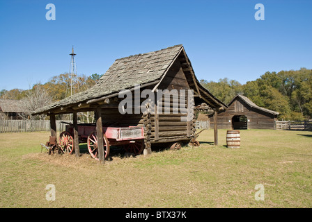 Eine Blockhaus Typ Lagerung Schuppen mit einem alten Wagen neben ihm zu sitzen. Es ist eine alte Scheune im Hintergrund. Stockfoto