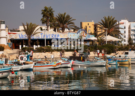 Boote im Hafen von Ayia Napa, mit Restaurants dahinter, Zypern. Stockfoto