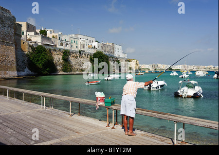 Ein Mann Angeln auf einem Steg an Otranto Hafen, Apulien, Italien Stockfoto