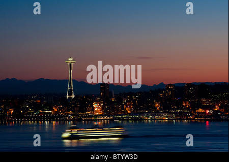 Ein wunderschönen Sonnenaufgang leuchtet der Space Needle und eine Fähre bringt Pendler in die Innenstadt von Seattle, Washington. Stockfoto