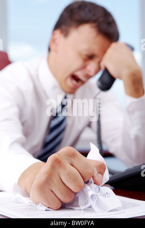 Leiden Geschäftsmann zerknittern Dokument mit gedrückter Telefonhörer Stockfoto