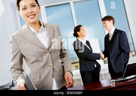 Porträt der schönen Geschäftsfrau im Anzug auf Hintergrund der Handshake-Partner Stockfoto