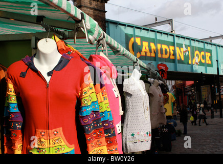 Klamotten auf einem Marktstand mit Camden Lock-Brücke im Hintergrund Stockfoto