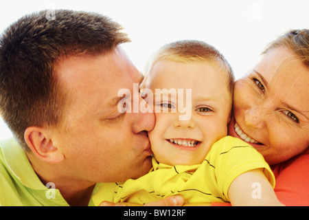 Porträt von glückliches Kind wird von seinen Eltern geküsst Stockfoto