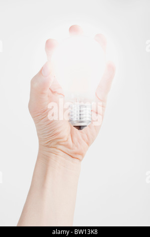 Hand hält eine leuchtende Glühbirne Stockfoto