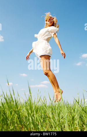 Foto des glücklichen Mädchen springen über grünen Rasen am Sommertag Stockfoto