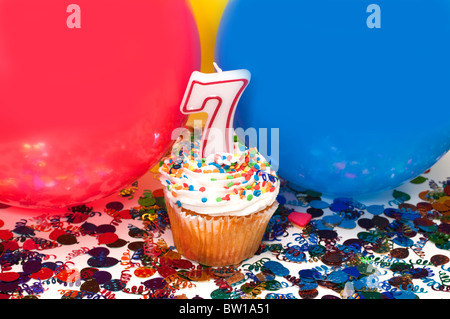 Feier mit Luftballons, Konfetti, Cupcake und Nummer 7 Kerze. Stockfoto